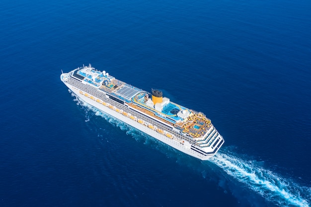 Cruise ship liner sails in the blue sea leaving a plume on the surface of the water seascape. Aerial view The concept of sea travel, cruises.