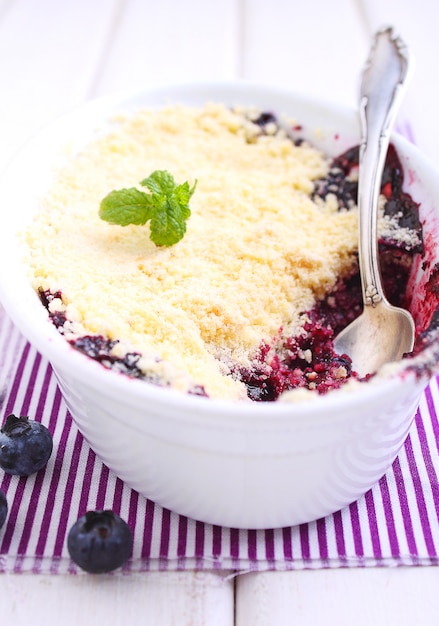 Crumble with blueberry, bilberry in white plate on a white background.