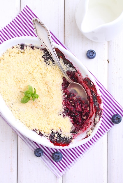 Crumble with blueberry, bilberry in white plate on a white background.