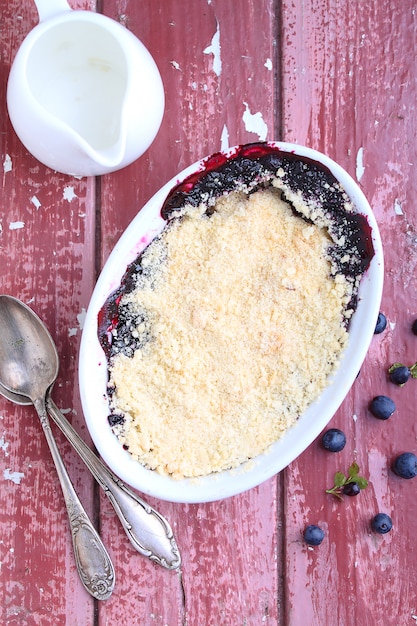 Crumble with blueberry, bilberry in white plate