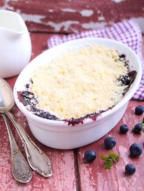 Crumble with blueberry, bilberry in white plate