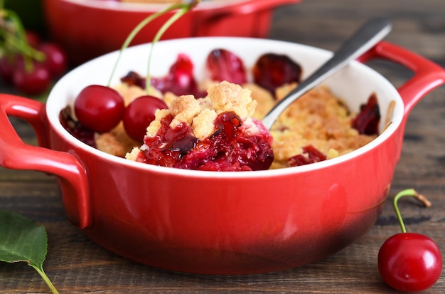 Crumble with cherries and nuts on a wooden background