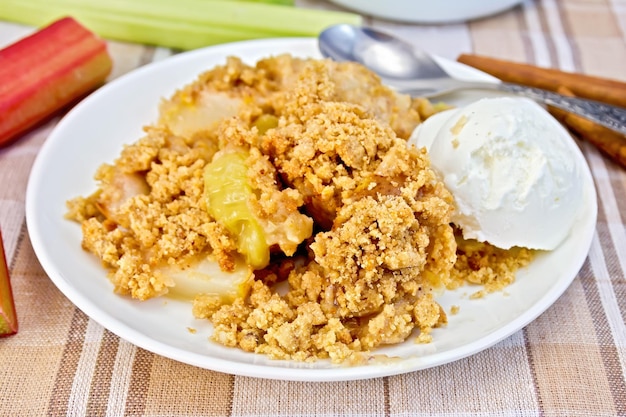 Crumble with rhubarb and ice cream in bowl on linen tablecloth