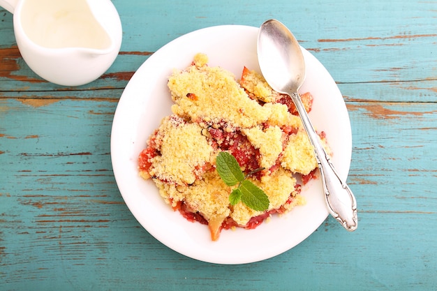 Crumble with strawberries in white plate on a blue background