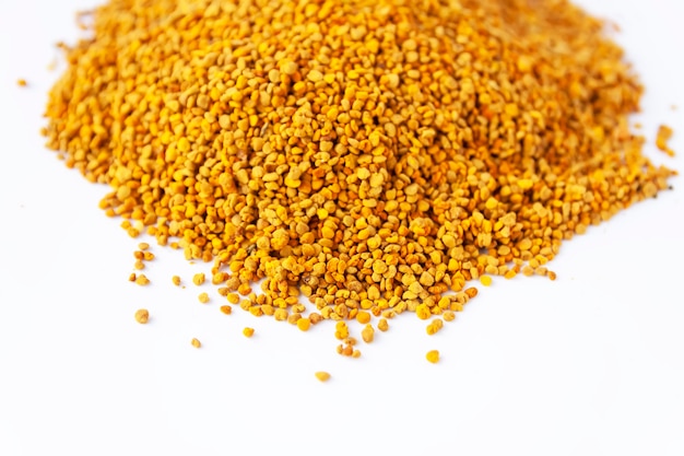 Crumbled bee pollen granules on white background close up