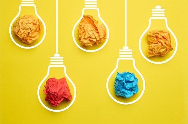 Photo crumpled balls of paper inside an electric lamp on a yellow background concept of new ideas brainstorming