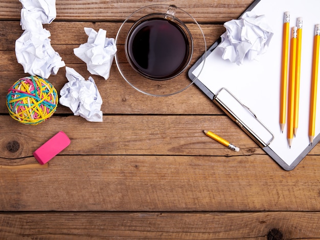 Crumpled paper balls with pencil clipboard on wooden background