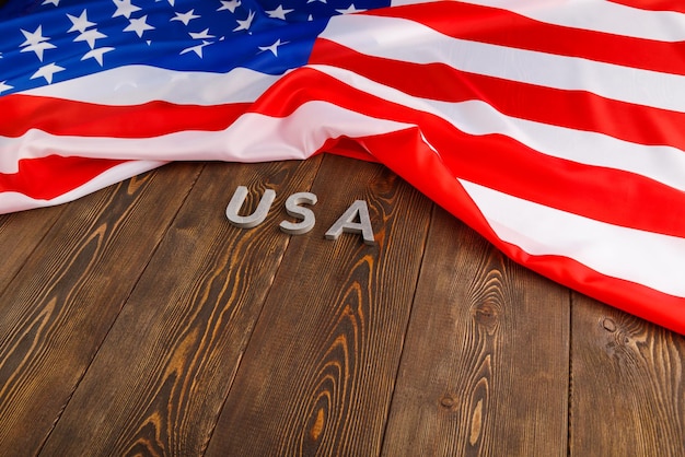 Crumpled United States of America flag and with word USA laid with on flat textured wooden surface background