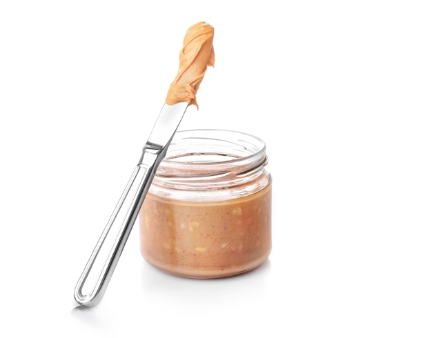 Crunchy peanut butter in glass jar isolated on white