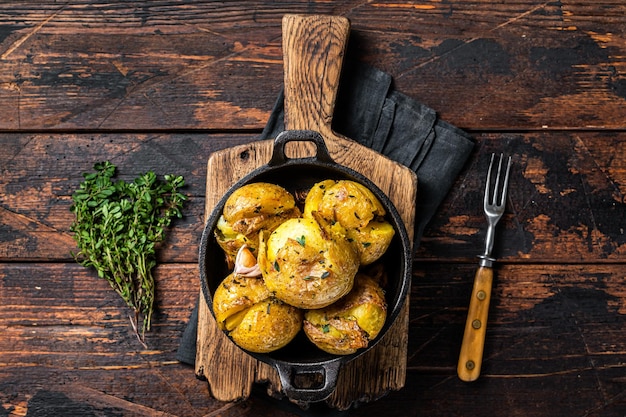 Crushed Broken potatoes baked in oil with herbs Wooden background Top view