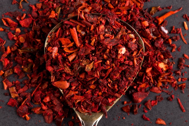 Crushed paprika in an iron spoon on a stone table. copyspace.