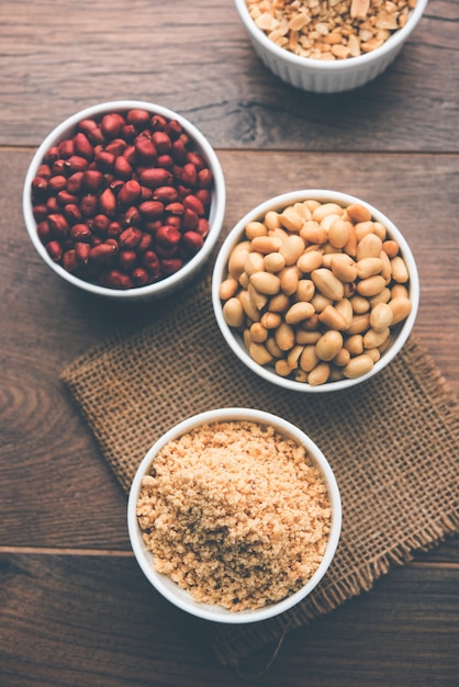 Crushed peanuts or mungfali powder with whole and roasted groundnut. Served in a bowl over moody background. Selective focus