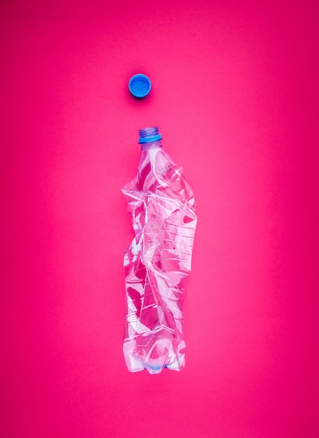 Crushed PET bottle closeup on vivid pink fashionable background