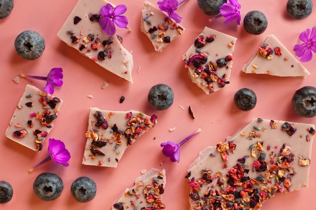 Crushed pink chocolate with blueberries and flowers broken bars with nuts and sublimated raspberry