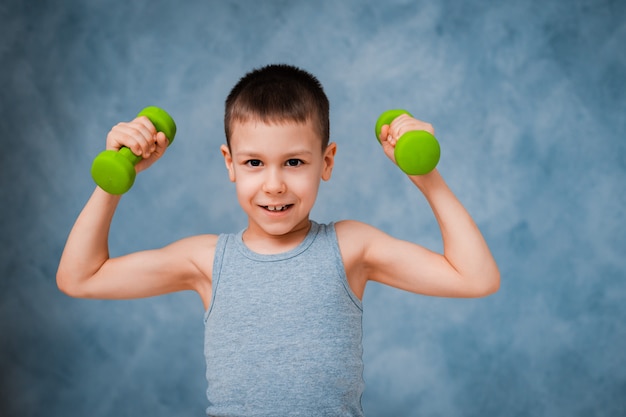 Cry sports baby boy emotionally shows his arm bicep muscle strength with dumbbells