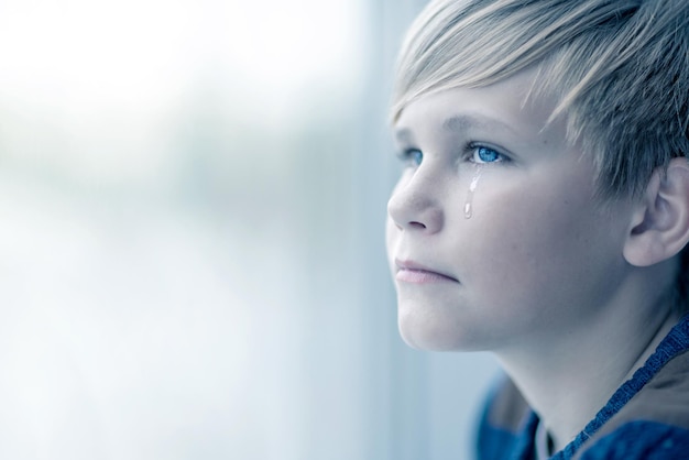 Crying boy looks out the window