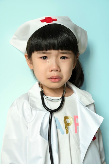 Crying little asian girl in medical uniform with stethoscope