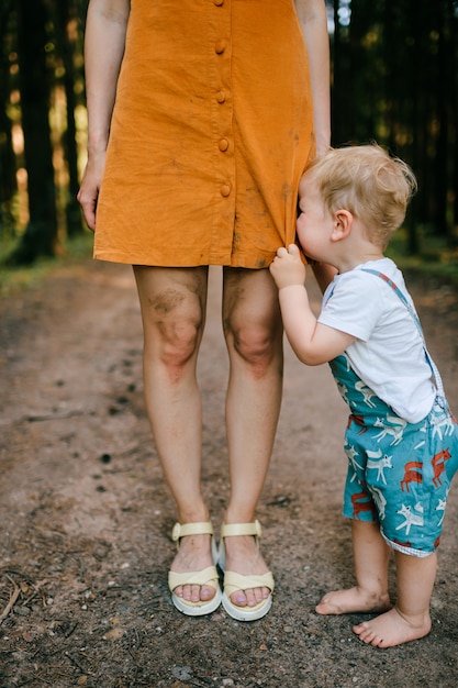 Crying little boy posing with mom's legs