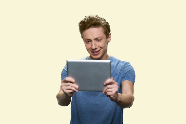 Crying teen boy is looking at the tablet