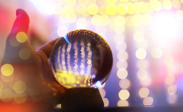 Crystal Ball on the floor with bokeh, lights behind. Glass ball with colorful bokeh light, celebration concept.