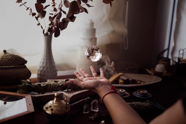 Photo a crystal ball is floating above a woman's hand on her esoteric witch altar