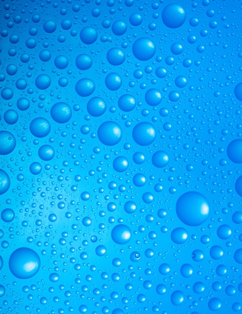 Crystal clear water drops over blue background. close up of water drops