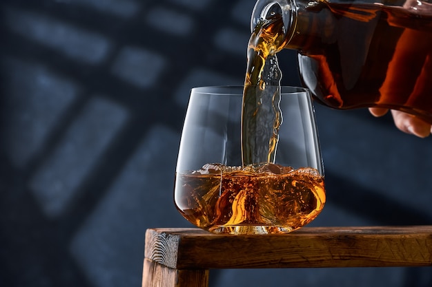 Crystal glass of whiskey with ice on a wooden counter