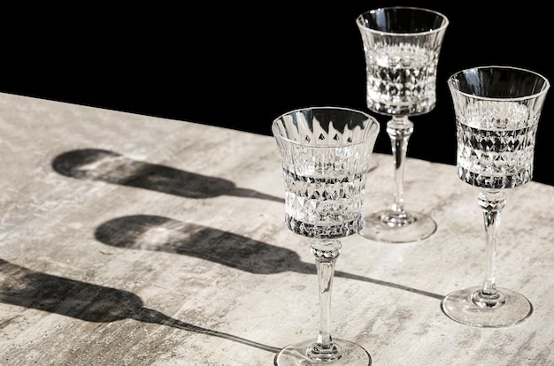 crystal wine glasses with wine on gray background hard lights long shadows wine testing monochrome