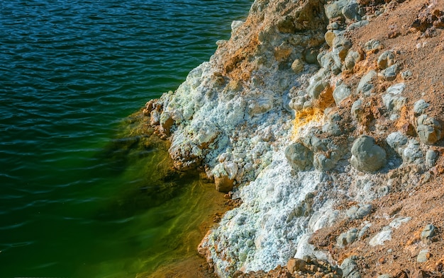 Crystals of iron sulfate and contaminated water at a shore of an abandoned open pit copper mine