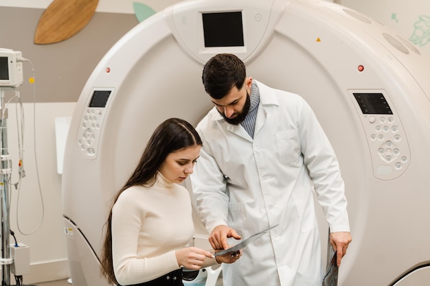 CT Doctor consulting patient and showing brains xray to patient in computed tomography room CT scan radiologist showing xray of brains to girl patient in computed scanning room