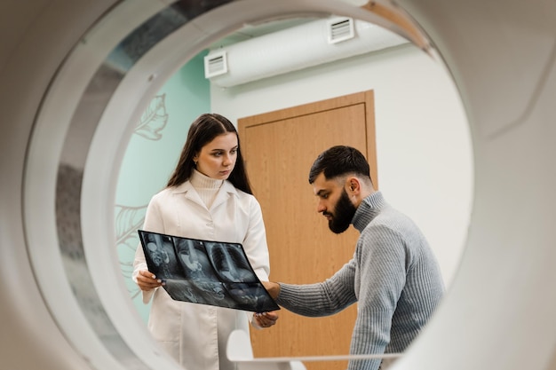 CT scan radiologist showing xray of abdomen to man patient in computed scanning room CT Doctor consulting patient and showing chest xray to patient in computed tomography room