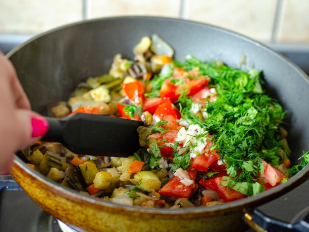 Cubes of fresh vegetables are fried in pan. 