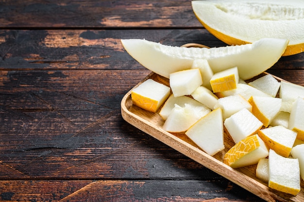 Cubes of sliced yellow melon on a wooden tray