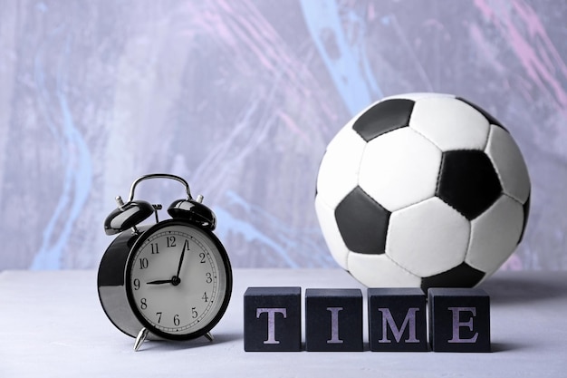 Cubes with alarm clock and soccer ball on color background Time concept