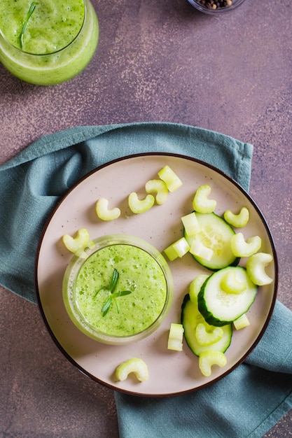 Cucumber and celery smoothie for vegetarian antioxidant diet in glass on table top and vertical view