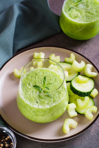 Cucumber and celery smoothie for vegetarian antioxidant diet in glass on table vertical view