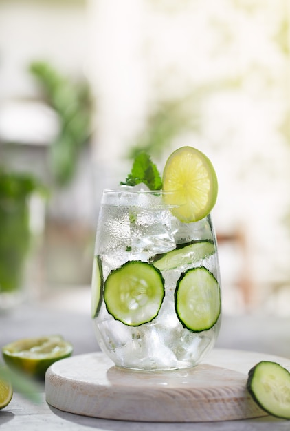 Cucumber cocktail with lime against the hedge in garden