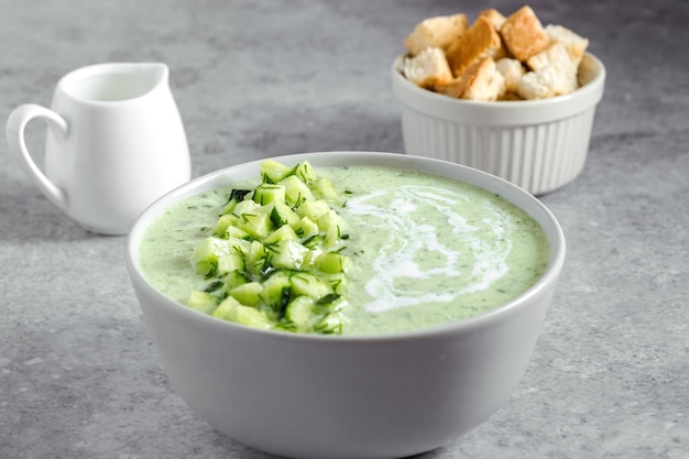 Cucumber Gazpacho Green fresh cold summer soup on gray background concept of vegan cuisine