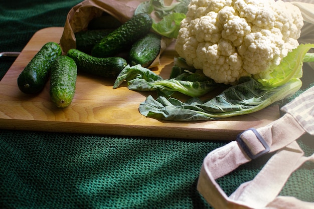 Cucumbers and cauliflower lie on a wooden cutting board