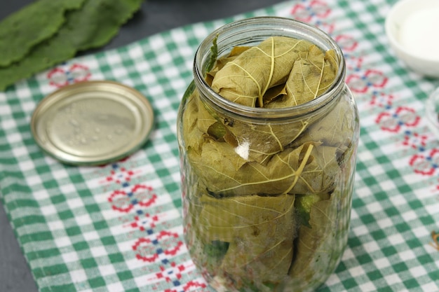 Cucumbers in grape leaves are placed in a jar of garlic and dill for pickling, the preparatory process