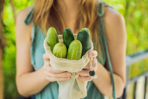 Cucumbers in a reusable bag in the hands of a young woman zero waste concept