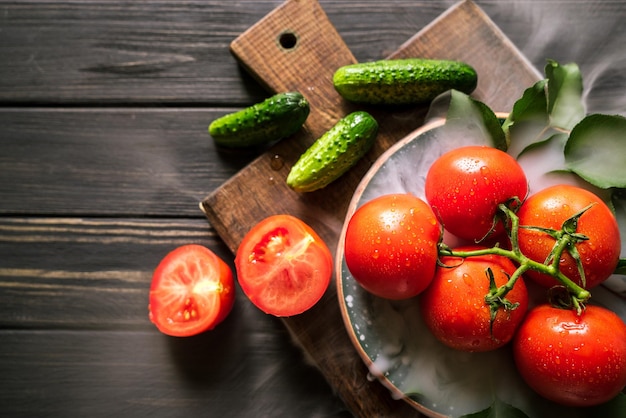 Cucumbers tomatoes and smoke on a black wooden background 6