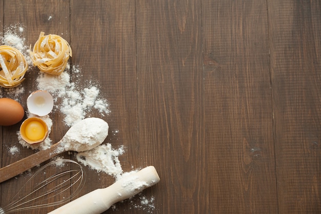 Cuisine composition with cracked eggs,kitchenware, flour. View from above