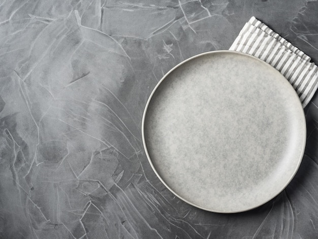 Culinary background with empty plate and napkin on a grey slate stone or concrete tableTop view wi