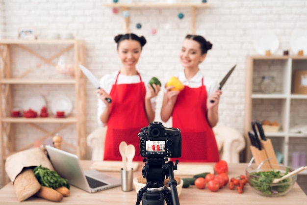 Photo culinary bloggers hold up peppers and knives.