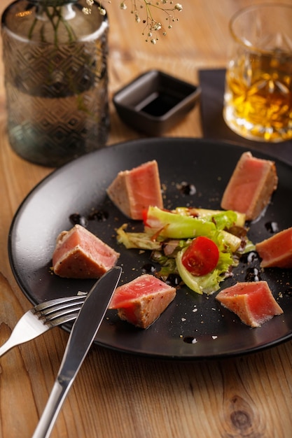 A culinary dish salmon steak on a black plate on a wooden table restaurant serving