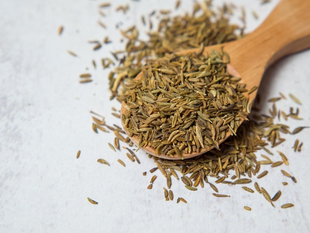 Cumin or cumin in wooden spoon isolated on light concrete background close up