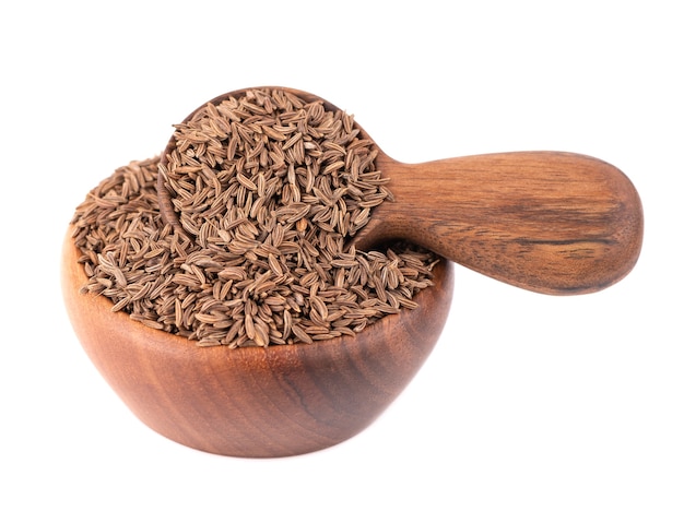 Cumin seeds in wooden bowl and spoon, isolated on white. Cumin seeds or caraway.