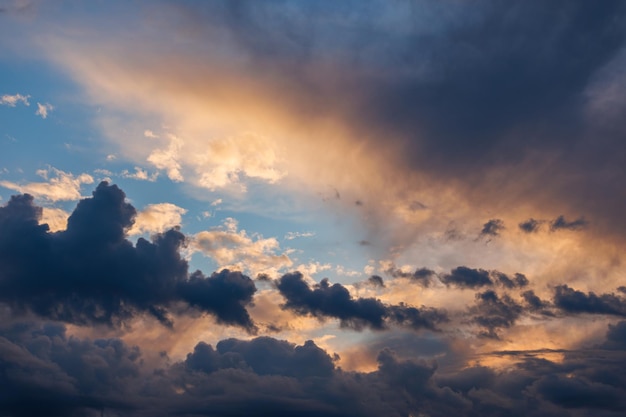 Cumulus clouds on evening sky backlit with sunset