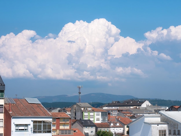 Cumulus clouds move towards the city of Monforte de Lemos approaching a storm in its lower part over the buildings of the town